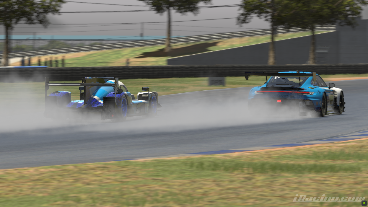 Two race cars are driving away from the camera in the rain